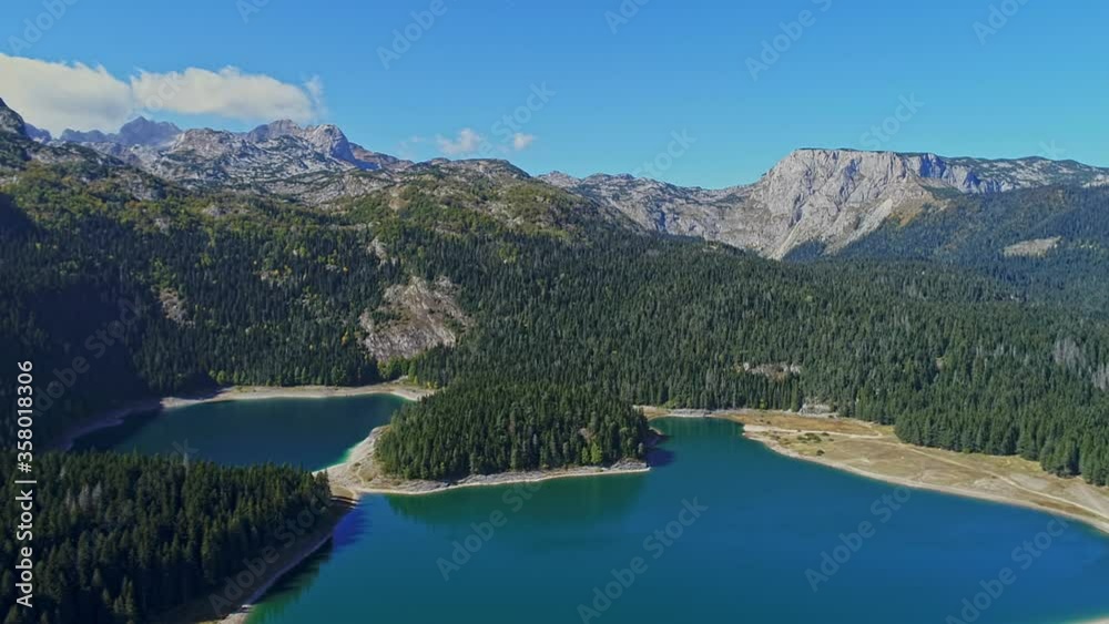 Aerial view of lakes between the mountains surrounded by pine forests and beautiful blue sky with clouds Aerial view of lakes between the mountains surrounded by pine forests and beautiful blue sky with clouds