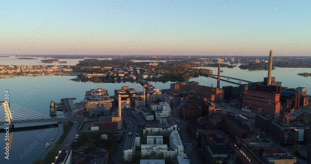 Aerial view overlooking the bridge and buildings in the Ruoholahti area, in Helsinki, during dawn, Lauttasaari district in the background, in Helsingfors, Finland - tracking, tilt down, drone shot