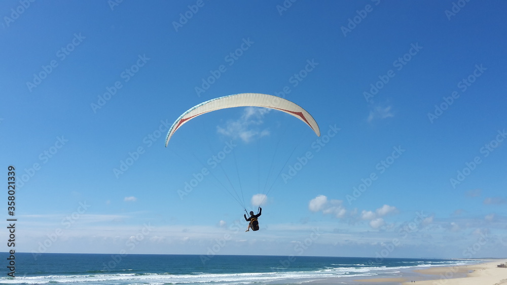 Paraglider fliegt über einen Strand am atlantische Ozean Paraglider fliegt über einen Strand am atlantische Ozean