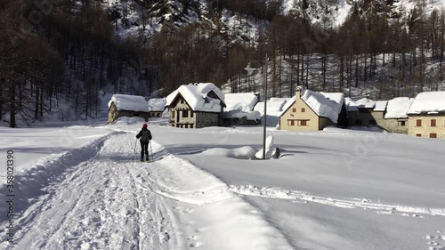 A hiker walks with snowshoes in the enchanting landscape of Alpe Devero in Piedmont Italy.