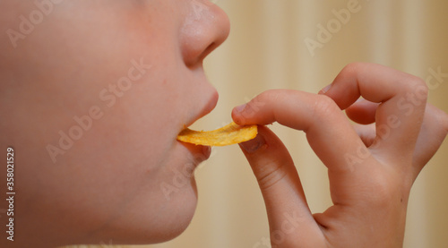 girl holds in hand and eats potato chips. female lips touch chips