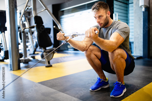 Young handsome man doing exercises in gym