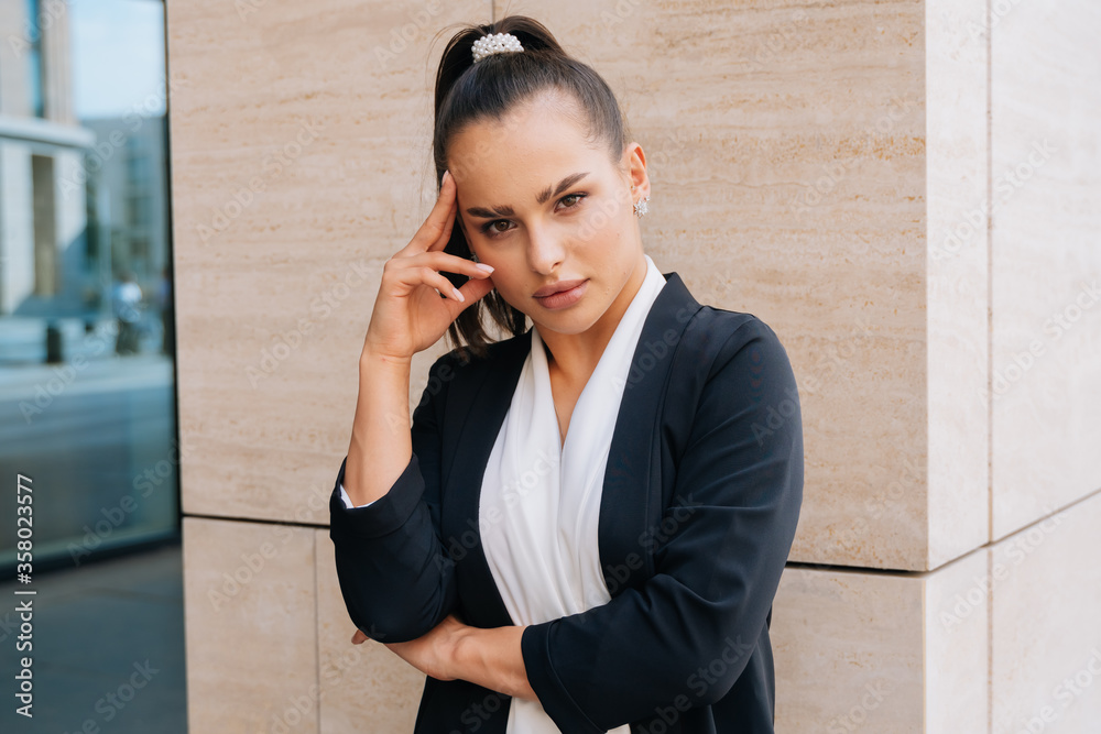 A brooding stylish girl looks to the side in a business suit. Average plan against the background of the business center A brooding stylish girl looks to the side in a business suit. Average plan against the background of the business center