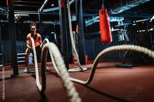 Powerful attractive muscular woman battle rope workout at the gym photo