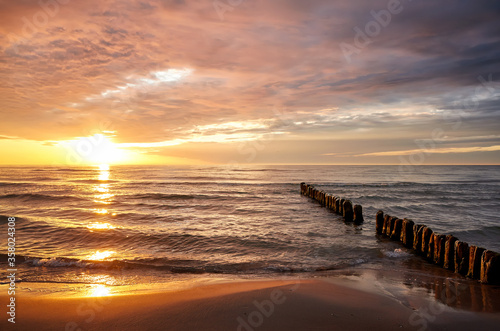 Beach with an old breakwater at beautiful sunset over sea.