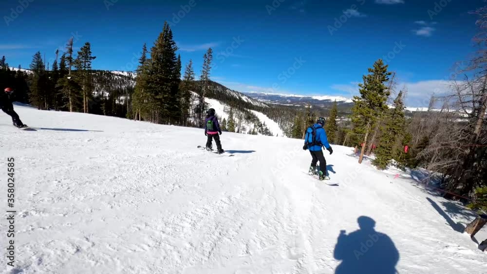 a group of snowboarders ride together on the groomer run at the ski resort in Colorado a group of snowboarders ride together on the groomer run at the ski resort in Colorado