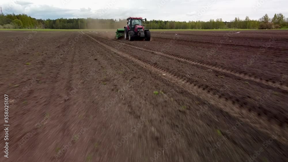 Beautiful aerial view of tractor and seeder sowing dusty brown field in sunny spring day, wide angle low altitude drone shot moving backwards Beautiful aerial view of tractor and seeder sowing dusty brown field in sunny spring day, wide angle low altitude drone shot moving backwards