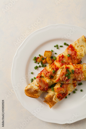 Baked pancakes with chicken in tomato sauce.