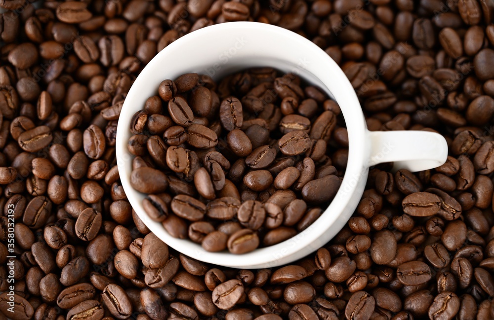 Natural coffee background. White cup steeped of coffee beans.