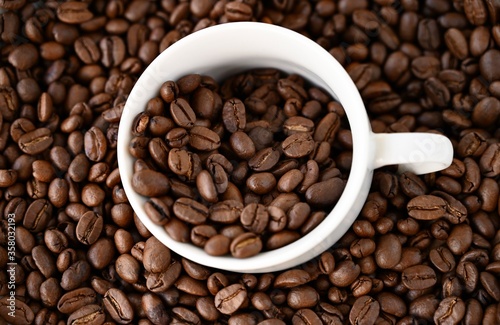 Natural coffee background. White cup steeped of coffee beans.