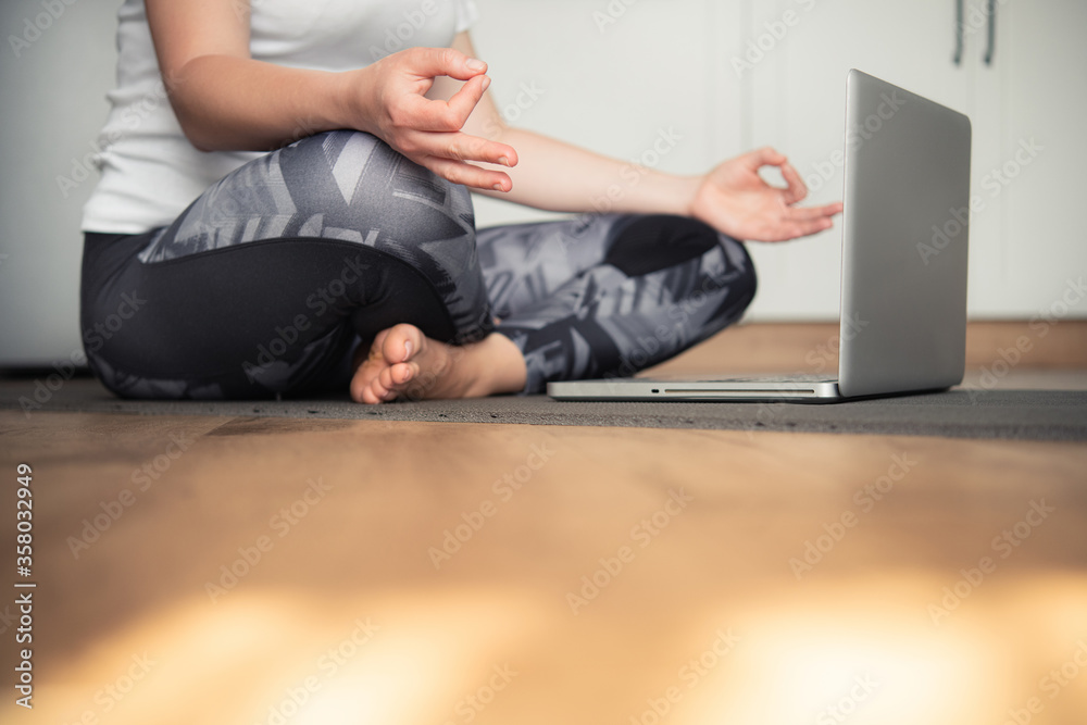 Woman doing yoga at home sitting on the floor in padmasana lotus position