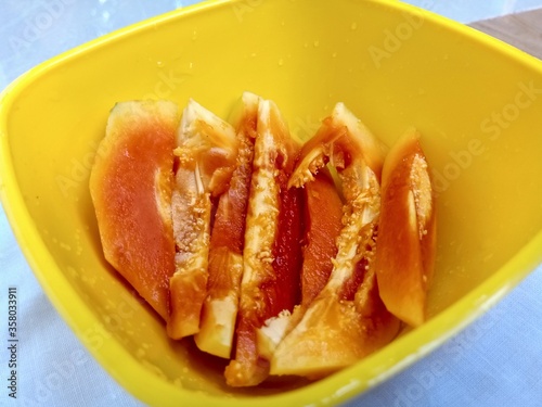 Organic papaya slices inside a yellow vessel.
