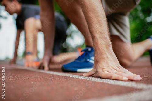 Close up of athlete men in sportswear in start position for running. 