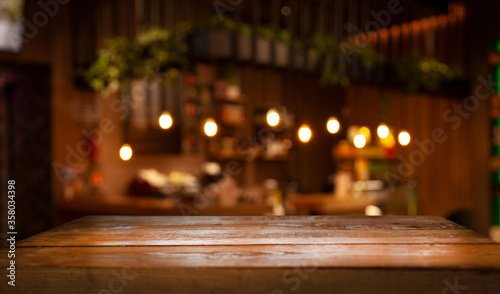 Empty wood table top on blur light gold bokeh of cafe restaurant in dark background © Egor