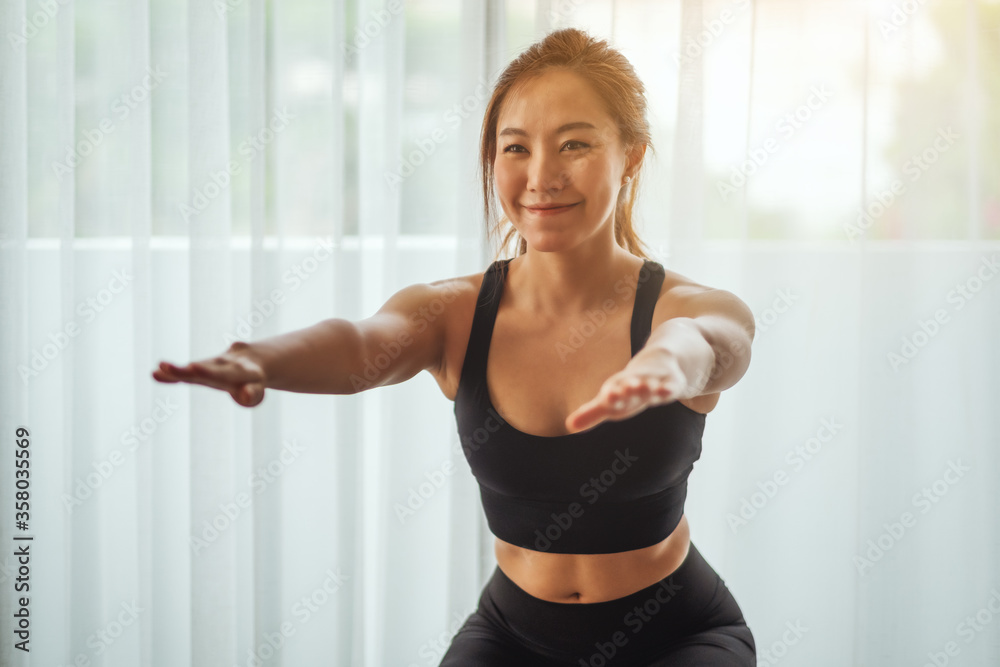 Closeup image of a beautiful young asian woman doing squats , workout at home