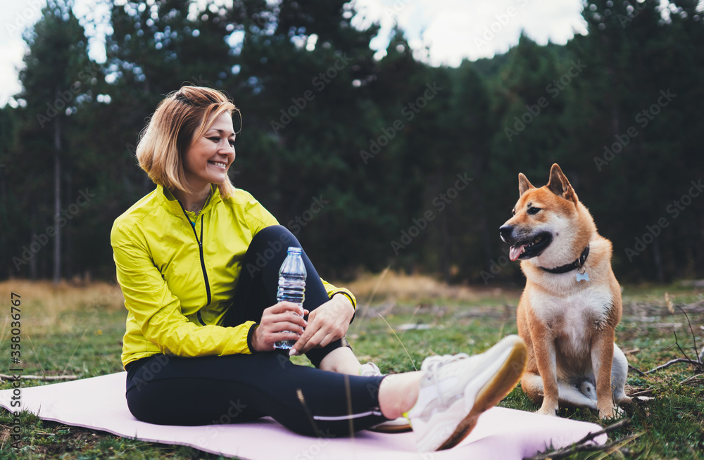 Φωτογραφία Smile girl  with pet together relax after exercising outdoors, shiba inu dog on nature, fitness woman drink water from thirst isolation training outside