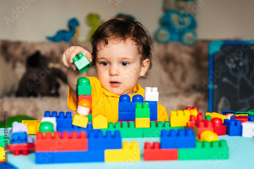 Child boy learns to build a house from blocks