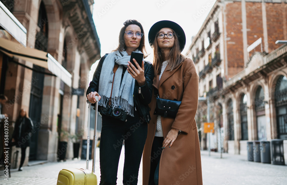 Φωτογραφία Girls plans trip on internet mobile phone, tourist using smartphone, hipster travels in Barcelona