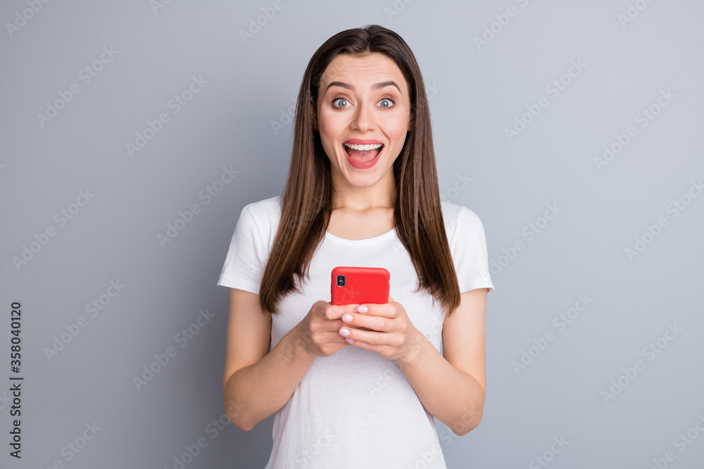 Close-up portrait of her she nice attractive lovely pretty charming cute overjoyed cheerful cheery girl using digital device having fun good news isolated over grey pastel color background Close-up portrait of her she nice attractive lovely pretty charming cute overjoyed cheerful cheery girl using digital device having fun good news isolated over grey pastel color background