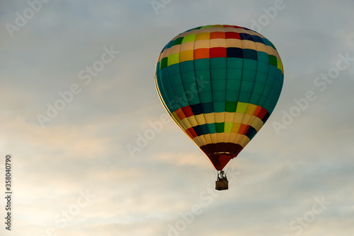 Colorful big hot air balloon flying against the cloudy sky © Konstantin