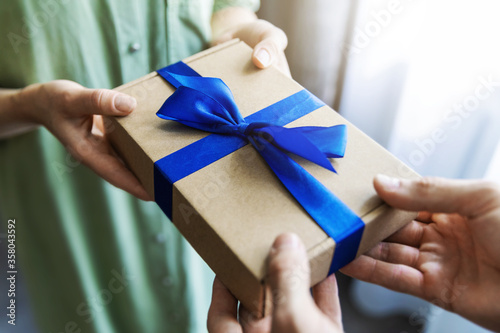 Obraz na plátně man giving gift box with blue ribbon to woman