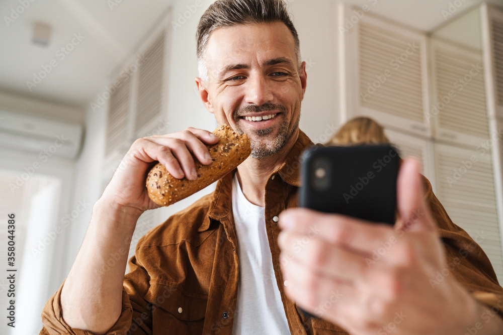 Image of joyful man taking selfie photo on smartphone while have lunch Image of joyful man taking selfie photo on smartphone while have lunch