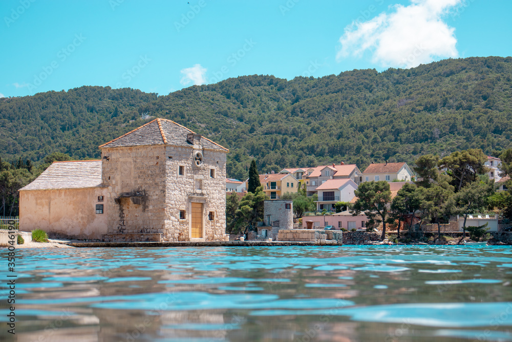 Small picturesque house of Saint Jerolim, stone greek style building standing on the waterfront of Starigrad,Hvar. Seen from the sea
