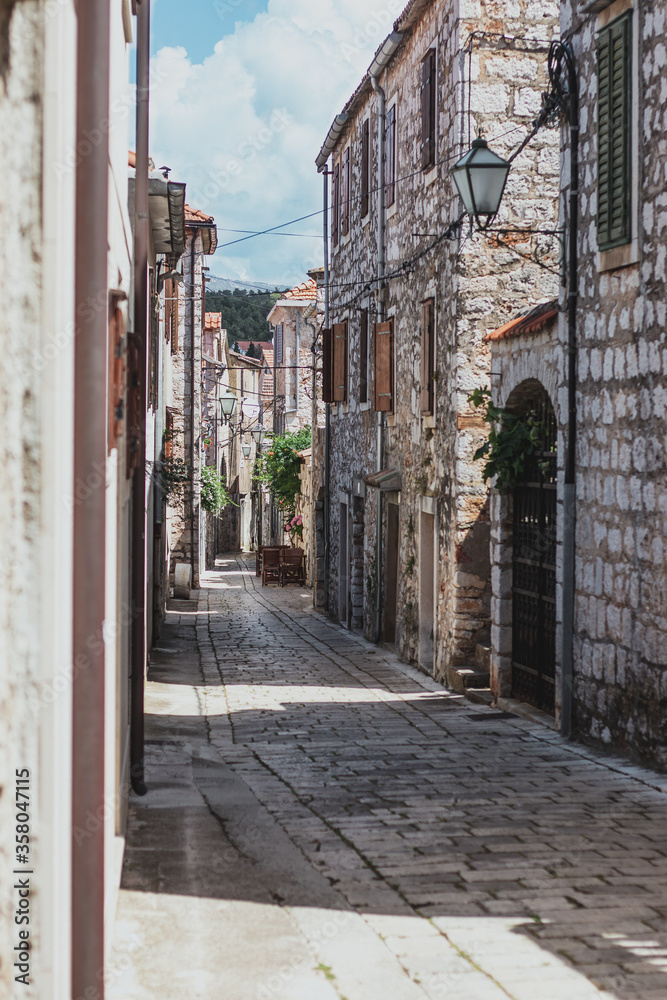 Narrow old streets in the town of Starigrad on the island Hvar. Old greek style stone houses and a narrow paved footroad going through them