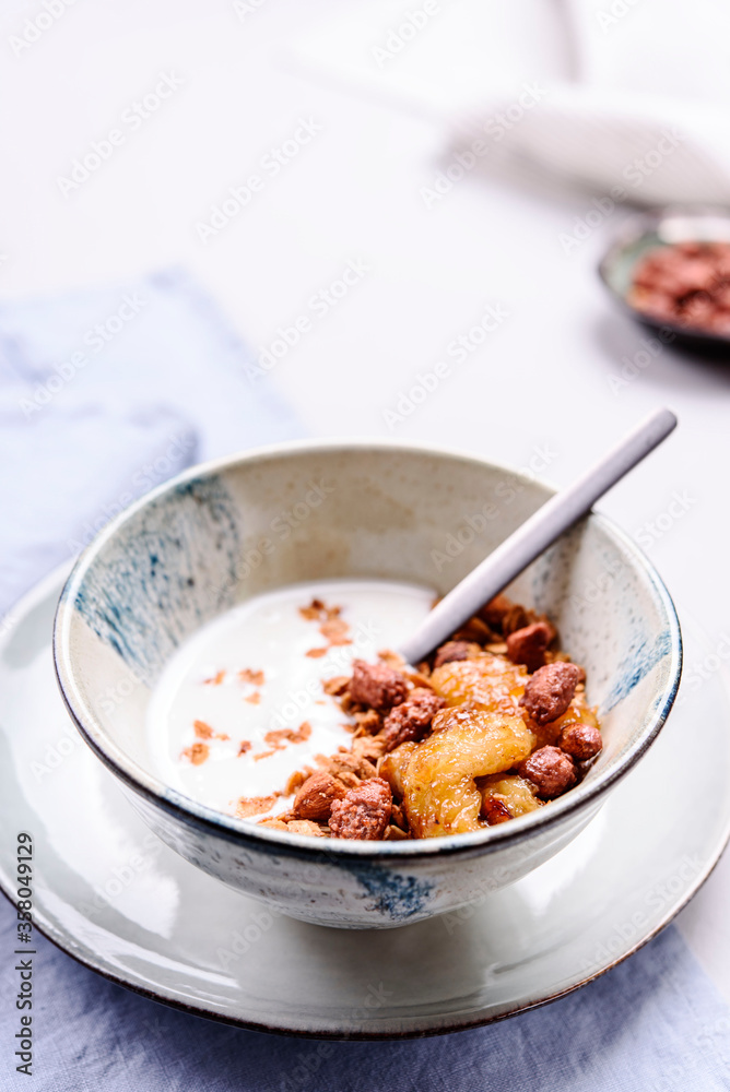 Healthy breakfast yogurt bowl with granola and caramelized bananas and nuts on grey concrete background. Selective focus Healthy breakfast yogurt bowl with granola and caramelized bananas and nuts on grey concrete background. Selective focus
