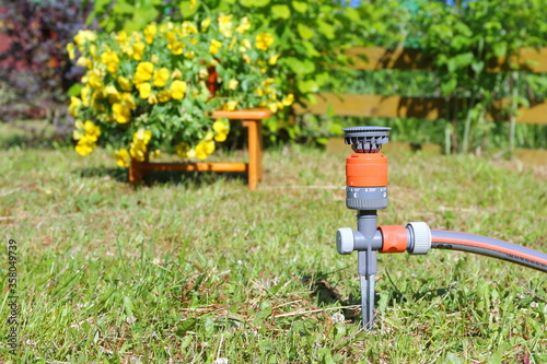 Garden watering equipment on the background of flowers and plants.