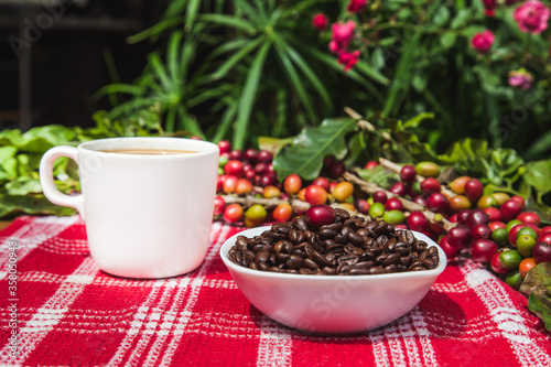 Coffee beans, coffee berries and a cup of coffee on the table.