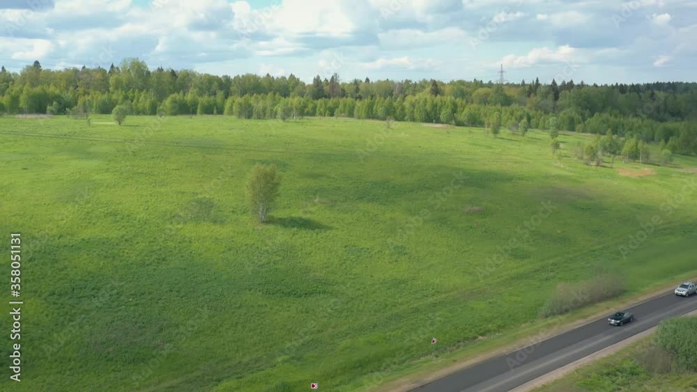 Highway road surrounded by green trees and grass in summer time, Russia. Drone zoom in high quality 4k footage of a green forest near road in rural area Highway road surrounded by green trees and grass in summer time, Russia. Drone zoom in high quality 4k footage of a green forest near road in rural area