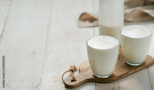 Kefir, buttermilk or yogurt with probiotics.Yogurt in glass on white wooden background.Probiotic cold fermented dairy drink.Gut health, fermented products, healthy gut flora concept. Copy space.Banner