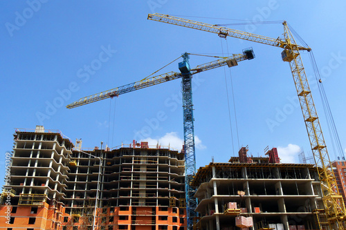 Construction site background. Hoisting cranes and new multi-storey buildings. Industrial background.