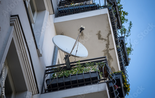 Foto Satellite dish of a parabolic antenna on a balcony, view from below