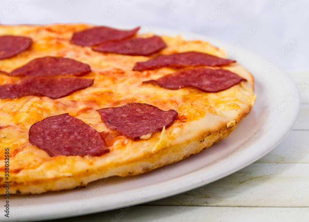 Pepperoni pizza on a white plate side view close up Pepperoni pizza on a white plate side view close up