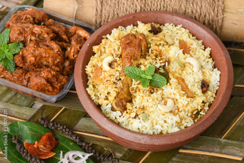 Spicy and delicious chicken biryani in traditional clay pot. Malabar biryani or Hydrabadi chicken biryani, Dum Biriyani, Chicken pulao basmati rice, herbs, raitha for Ramadan Kareem, Eid-Ul-Adha