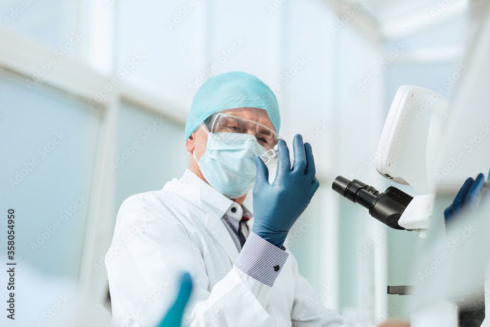 scientist in with an ampoule sitting at a laboratory table . scientist in with an ampoule sitting at a laboratory table .