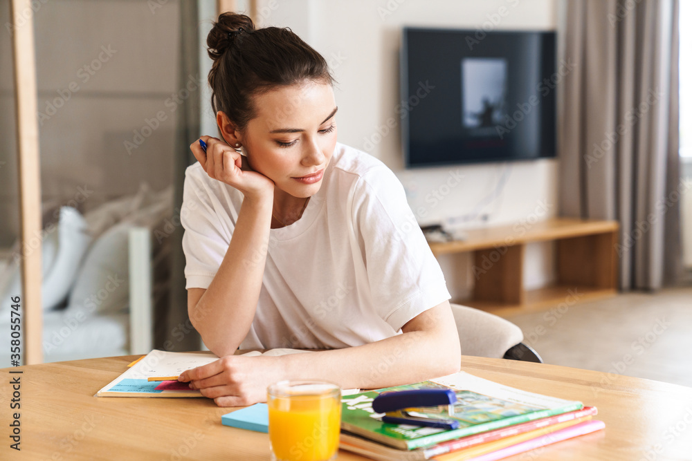 Photo of student woman doing homework while sitting at table Photo of student woman doing homework while sitting at table
