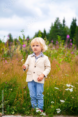 Little blond boy in a gentleman suit on nature.
