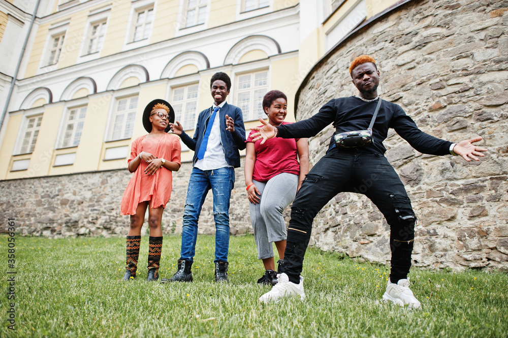 Fototapeta premium Four african friends having fun and dancing outdoors. Two black girls with guys.