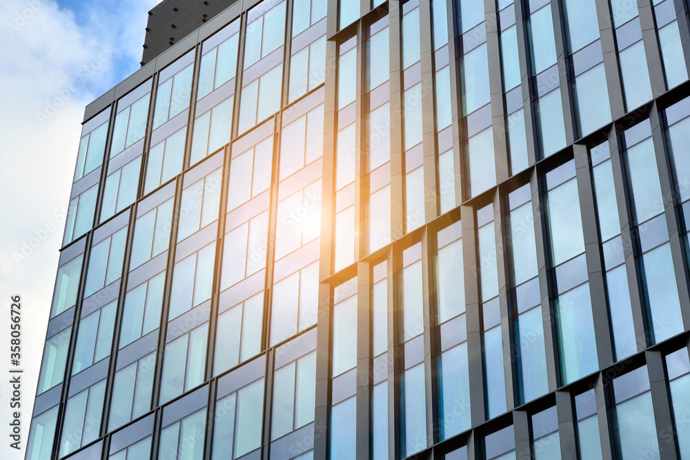 Facade texture of a glass mirrored office building. Fragment of the facade. Bottom view of modern skyscrapers in business district in evening light at sunset with lens flare filter effect. Facade texture of a glass mirrored office building. Fragment of the facade. Bottom view of modern skyscrapers in business district in evening light at sunset with lens flare filter effect.