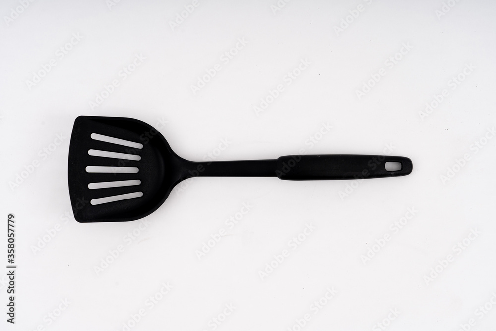 spade of frying pan made from plastic on white background selective focus, kitchen flipper