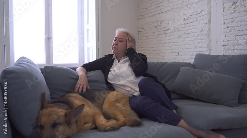 Depressed senior old woman crying on couch with pet dog as only Companion. Sad and tired widower amid COVID-19 pandemic. Coronavirus death, lockdown, social distancing and Mental health.