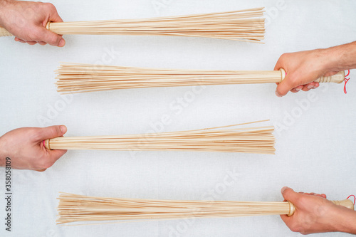 Top view of bamboo brooms in hands of two masseurs on white background. photo