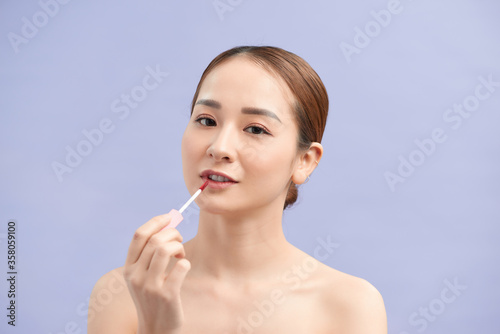 Wallpaper Mural Pretty trendy stylish girl testing new lip gloss isolated on violet background, perfection, wellbeing advertisement concept Torontodigital.ca