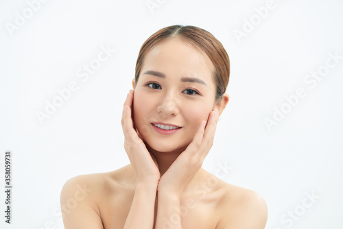 Beautiful young Asian woman with fresh clean skin that touches her face with both hands. Spa, cosmetology and beauty.