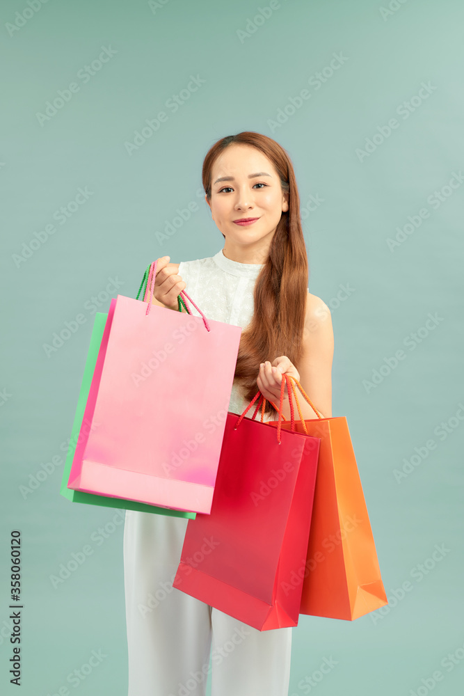 Smiling happy Asian woman shopping and holding bags