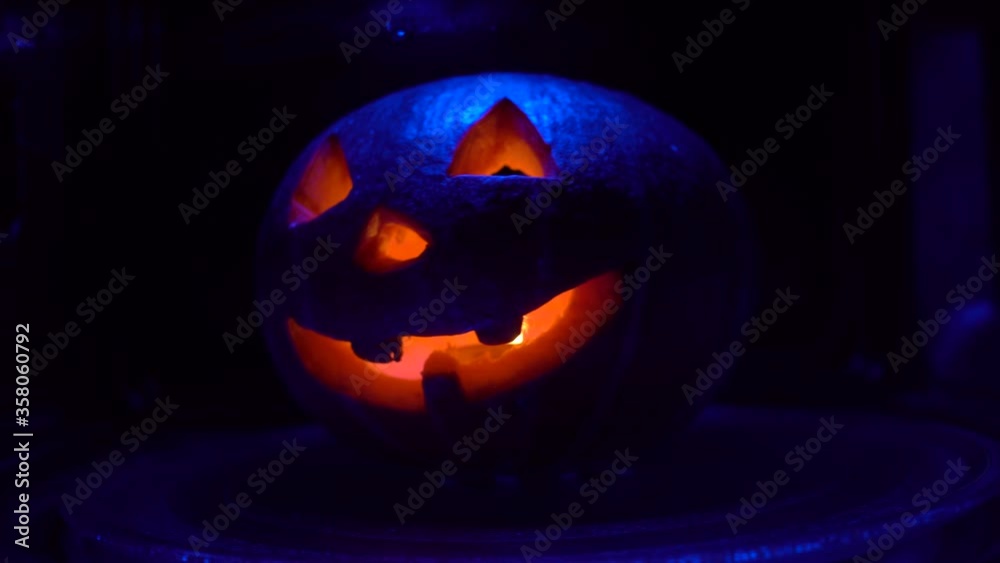 Funny pumpkin jack halloween decor on a black back spin background. Halloween pumpkin, carved by hand with sharp teeth, rotates around its axis in the microwave and glows from the inside. Funny pumpkin jack halloween decor on a black back spin background. Halloween pumpkin, carved by hand with sharp teeth, rotates around its axis in the microwave and glows from the inside.