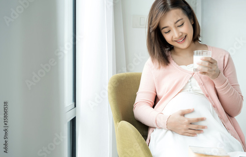 Young pregnant woman with glass of milk in the room